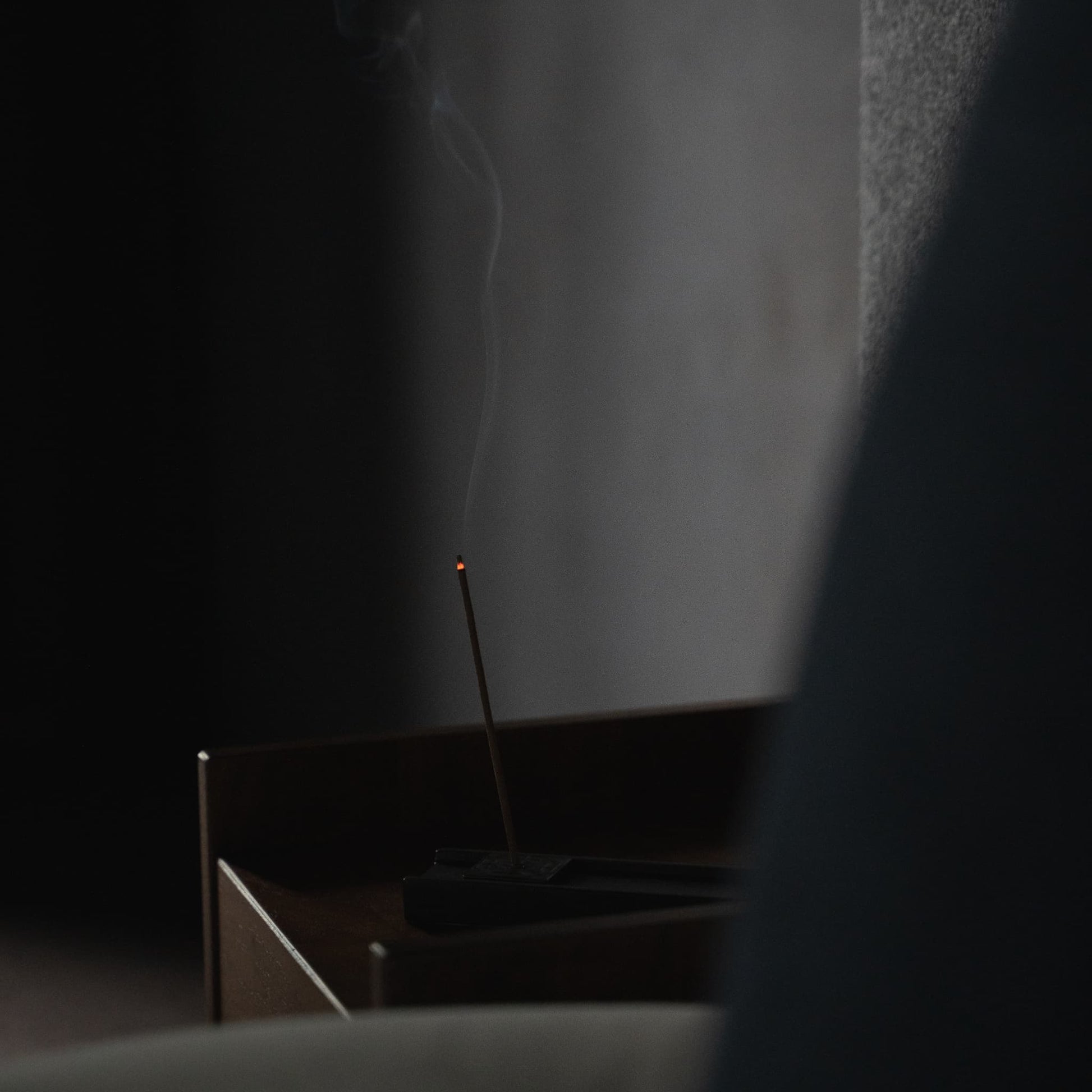 Ein Räucherstäbchen aus Hinoki-Holz, das auf einem Beistelltisch in einem Schlafzimmer im Japandi-Stil für ultimative Entspannung platziert ist.