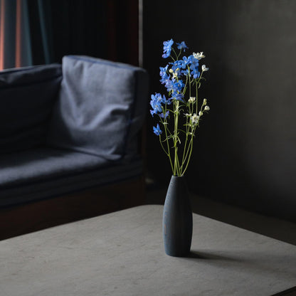 A beautiful cedar wood Ikebana vase with blue flowers, adding a pop of color to a minimalist gray living room.