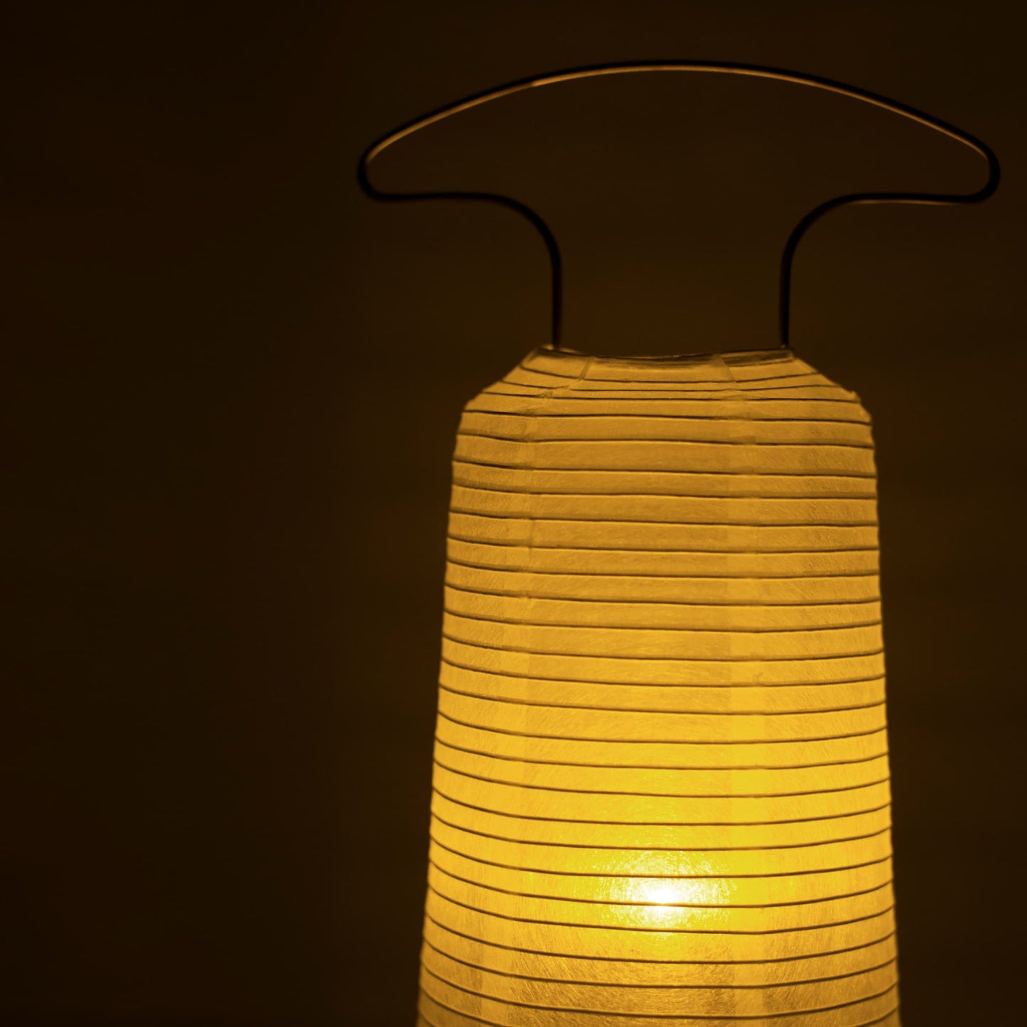 Close-up van een traditionele Japanse papieren lantaarn die warm licht uitstraalt in een donkere kamer