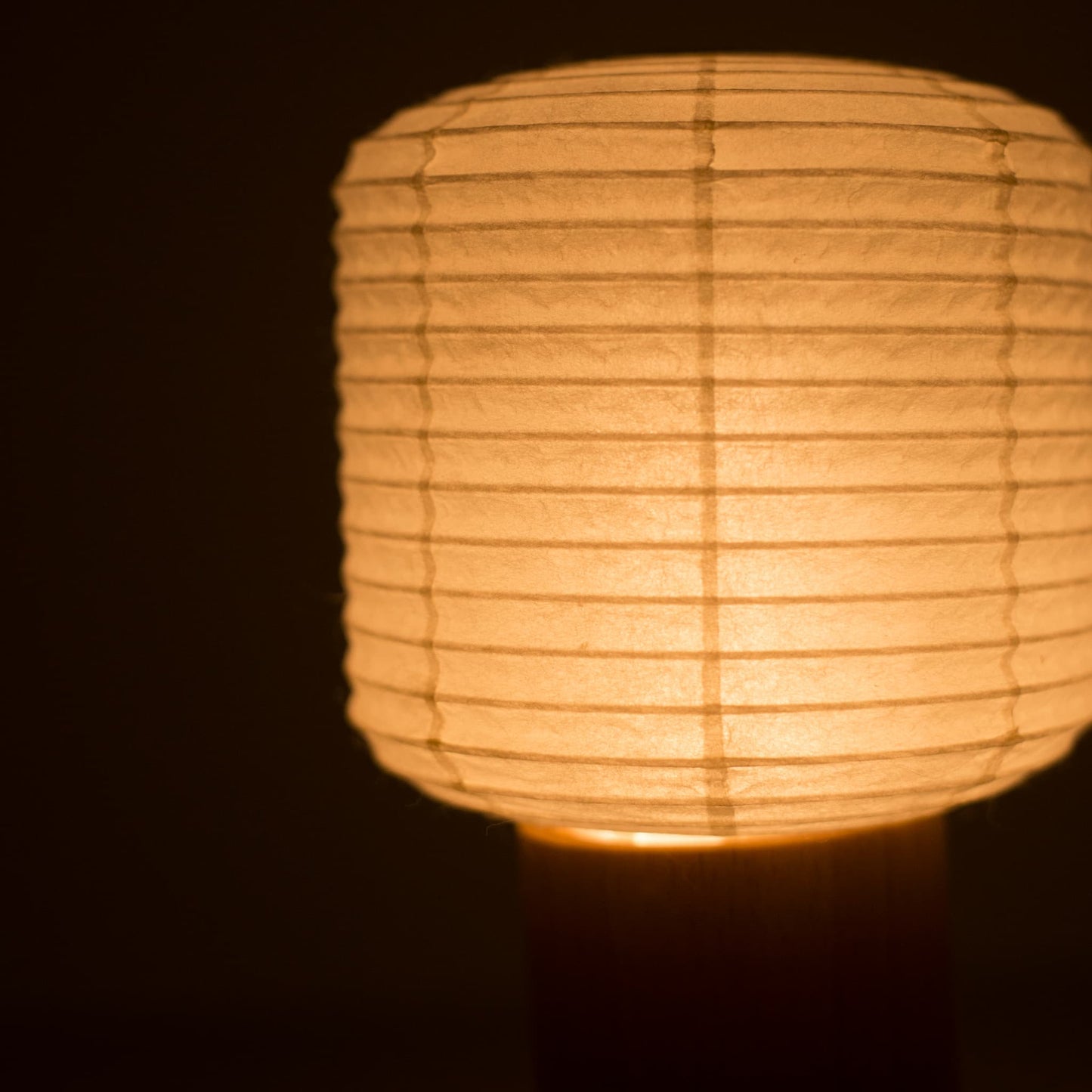 Nahaufnahme des oberen Papierlaternen-Abschnitts einer Yame-Taschenlampe, die in einem dunklen Raum warm leuchtet