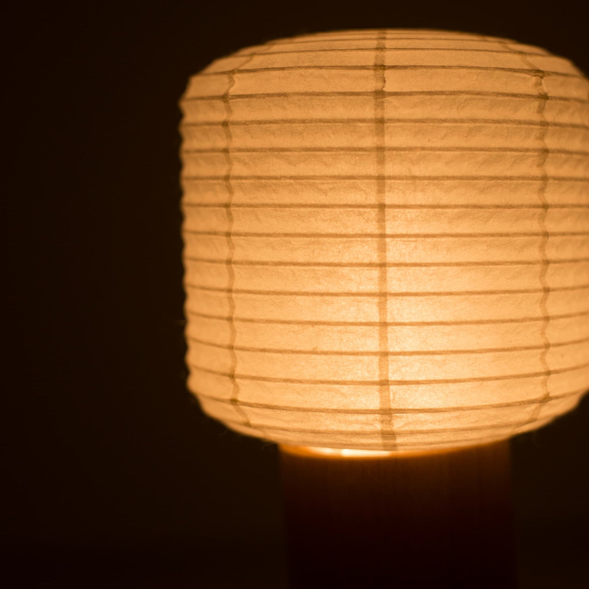 Nahaufnahme des oberen Papierlaternen-Abschnitts einer Yame-Taschenlampe, die in einem dunklen Raum warm leuchtet