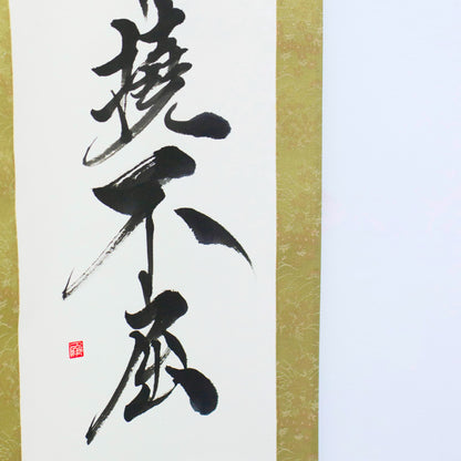 "Eine Nahaufnahme der unteren linken Ecke einer traditionellen japanischen Hängerolle, die die Kalligrafie '撓不屈' (Entschlossen und Unnachgiebig) zeigt"