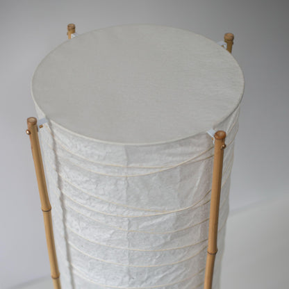 Gros plan de la partie supérieure d'une lampe japonaise cylindrique avec cadre en bambou et papier washi, fond blanc