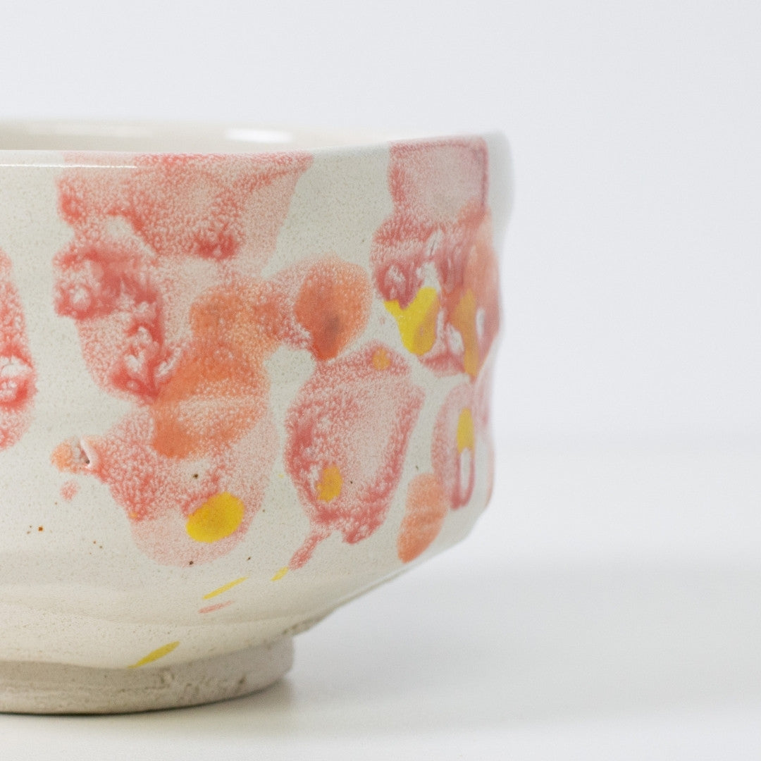Nærbillede af matcha chawan-skål "Flower" med rød-orange glasur, der fremkalder forårsblomsterblade.