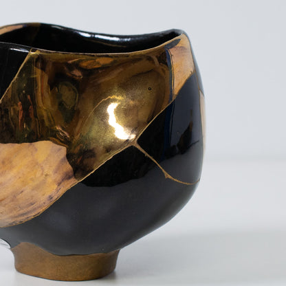 Gros plan d'un bol à matcha kintsugi mettant l'accent sur la laque dorée et la texture réfléchissante