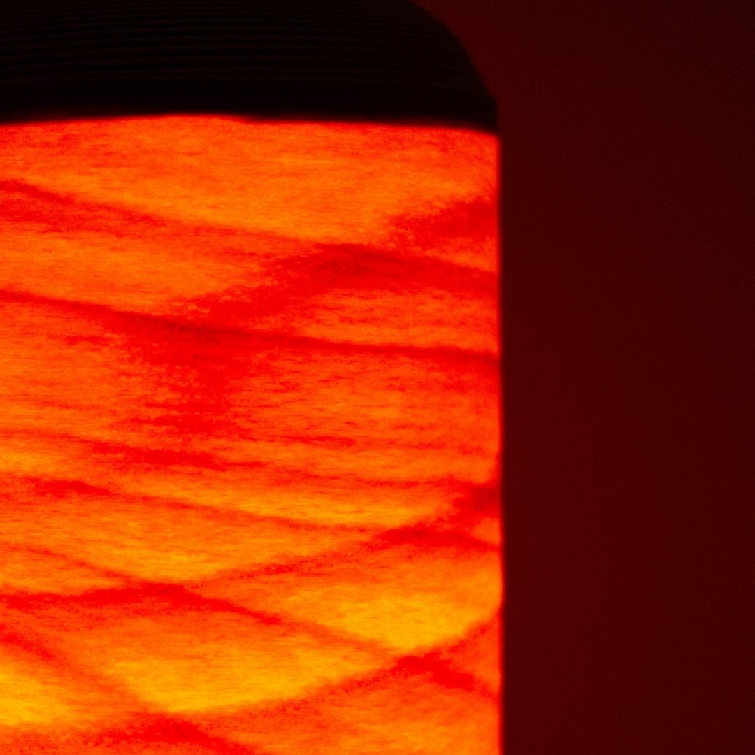 Close-up van een Japanse woonkamerlamp die als een vreugdevuur gloeit door dunne beukenhouten lamellen.