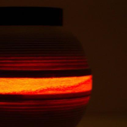 Close-up van een Japanse woonkamerlamp met een warme lichtband die door beuken houten lamellen schijnt.