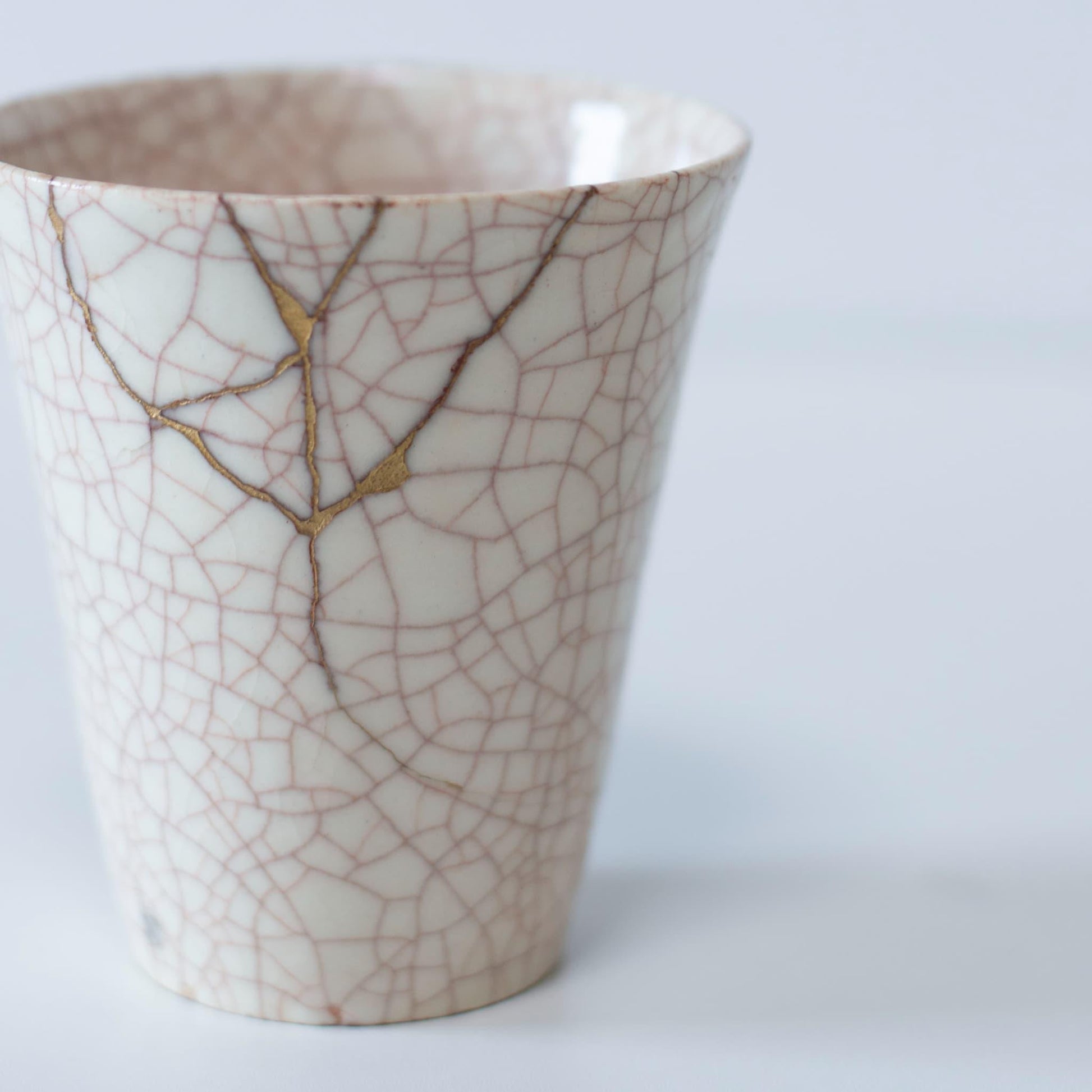 Kintsugi-repareret hvid kop og gaveæske af paulownia-træ, der symboliserer den japanske æstetik med at finde skønhed i ufuldkommenhed.