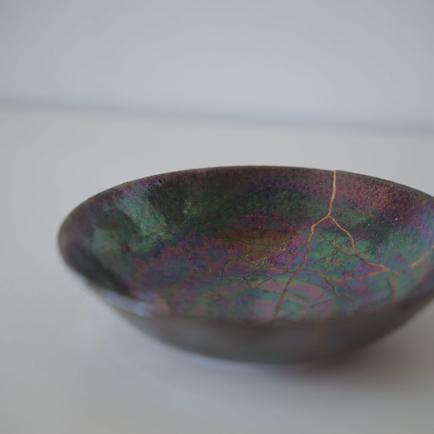 Tæt på siden af Kintsugi-skål "Ugle-tågen", der fremhæver de indviklede Kintsugi-reparationer