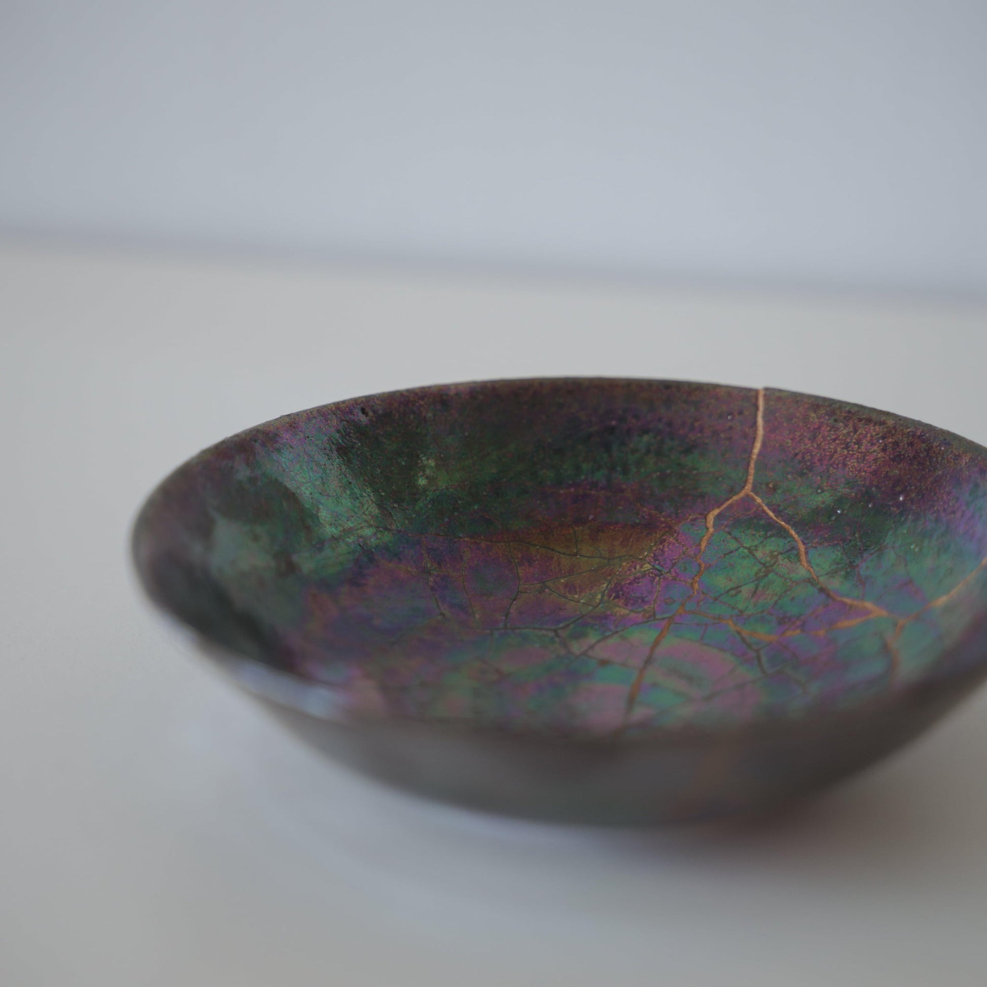Tæt på siden af Kintsugi-skål "Ugle-tågen", der fremhæver de indviklede Kintsugi-reparationer