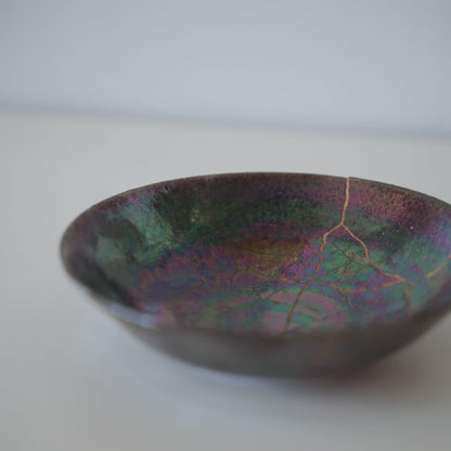Tæt på siden af Kintsugi-skål "Ugle-tågen", der fremhæver de indviklede Kintsugi-reparationer