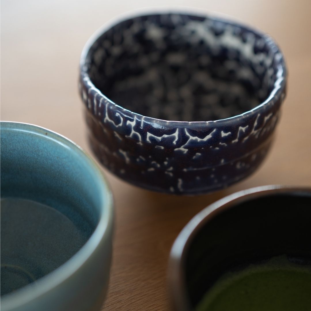samling af tre japanske matcha-skåle, med "Midnight Blue Kairagi"-skålen i midten, der viser dens unikke teksturerede glasur sammen med en lyseblå og en mørkebrun chawan.
