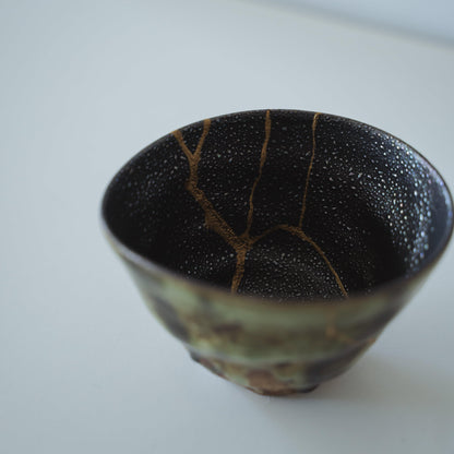 Indeni en dyb grøn te-skål repareret med Kintsugi, en traditionel japansk teknik, der viser skønheden i ufuldkommenhed.