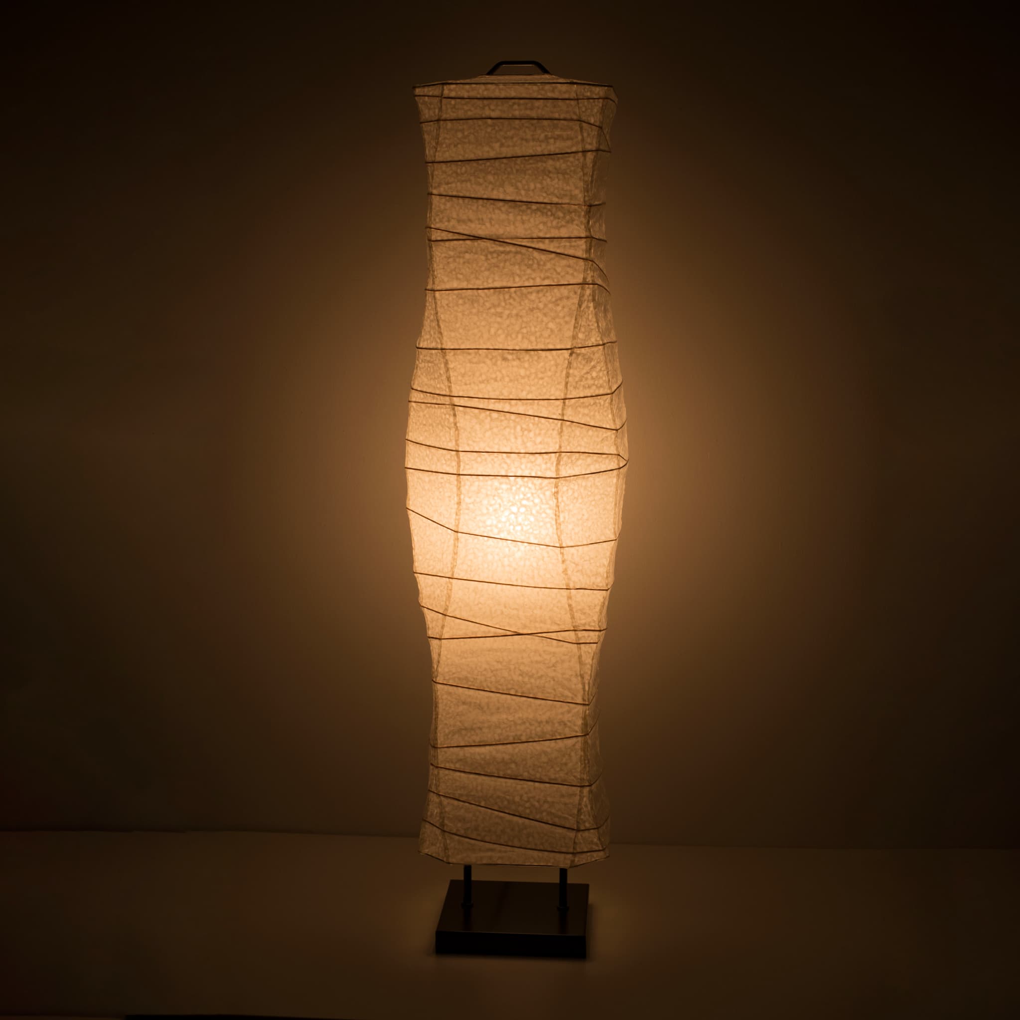"Une vue de face d'un lampadaire japonais en papier washi aux courbes douces et fluides, avec une lumière chaude sur un fond brun foncé"