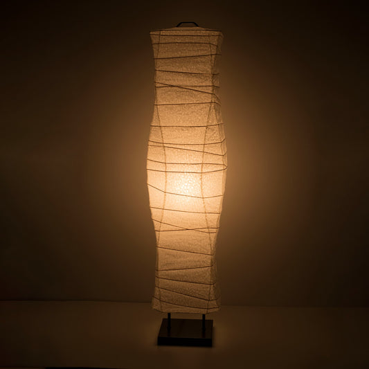 A front view of a Japanese washi paper floor lamp with smooth, flowing curves and a warm light on a dark brown background