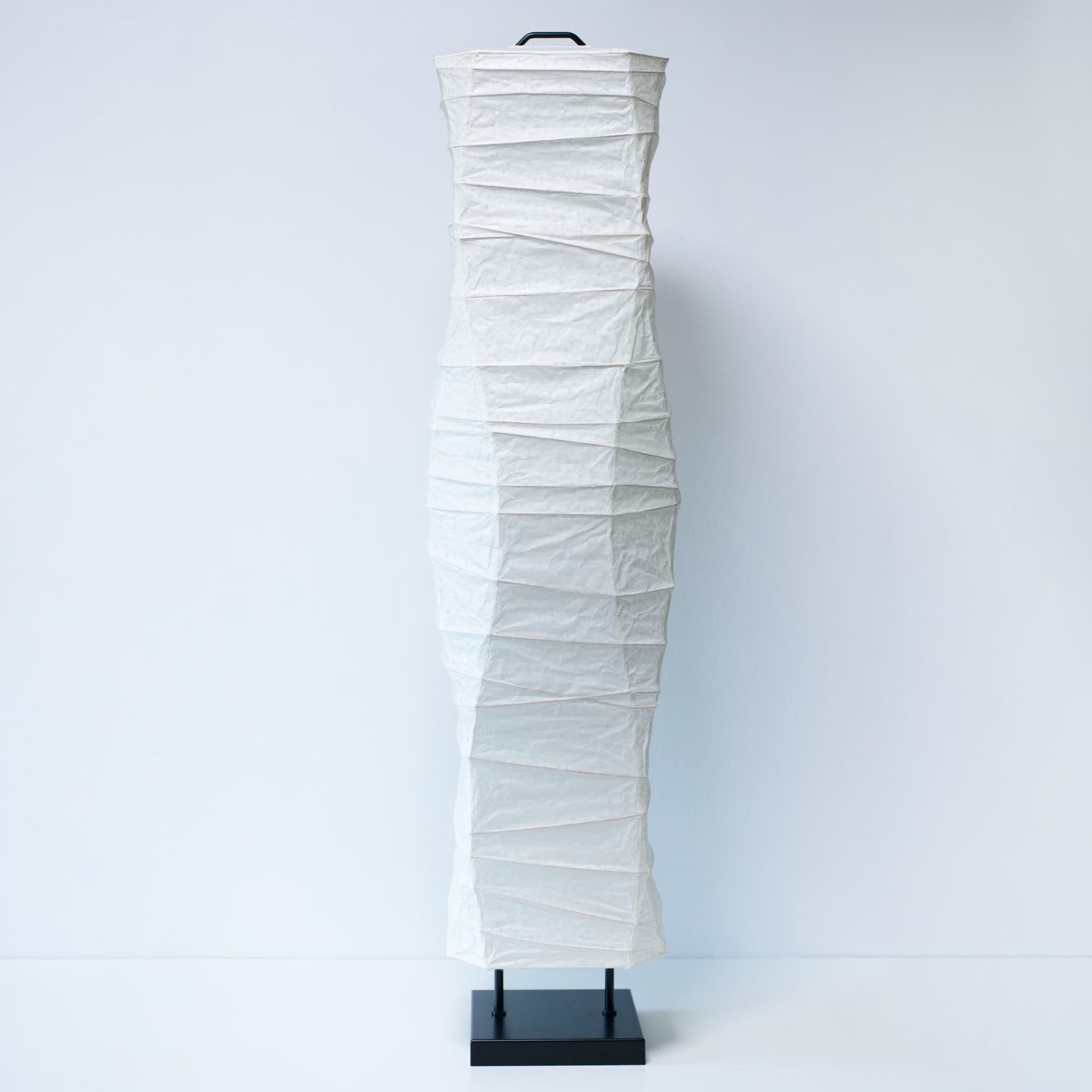 Une vue de face complète d'une lampe japonaise en papier washi aux courbes élégantes, photographiée sur un fond blanc épuré