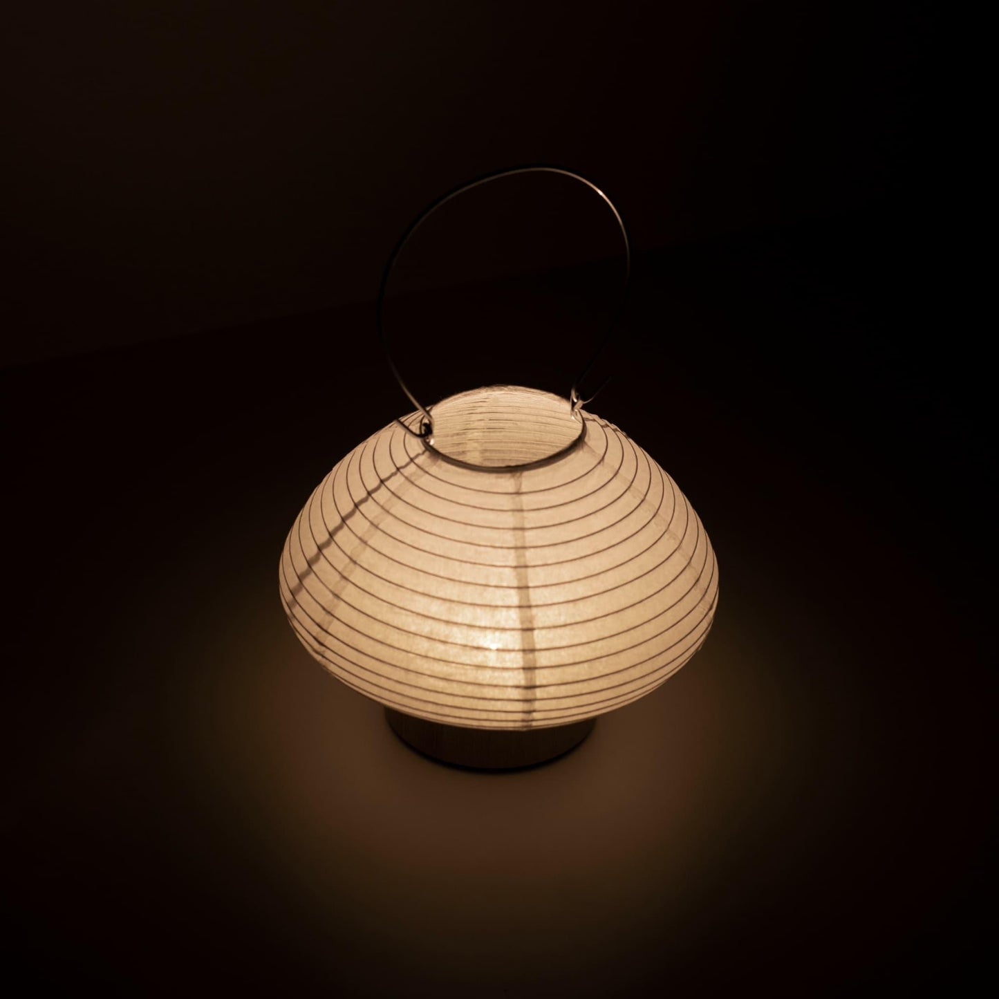 Detail of a portable paper table lamp crafted with Gifu lantern techniques and Mino washi paper, emitting a soft, warm light.