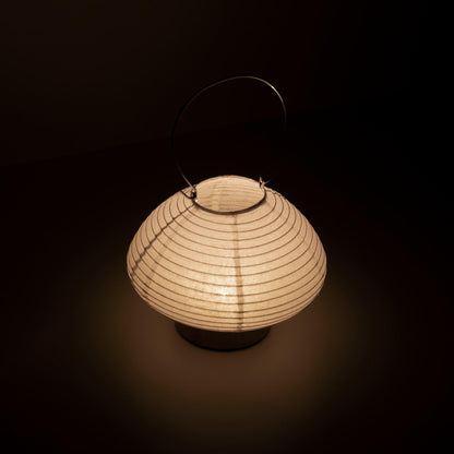 Detail of a portable paper table lamp crafted with Gifu lantern techniques and Mino washi paper, emitting a soft, warm light.