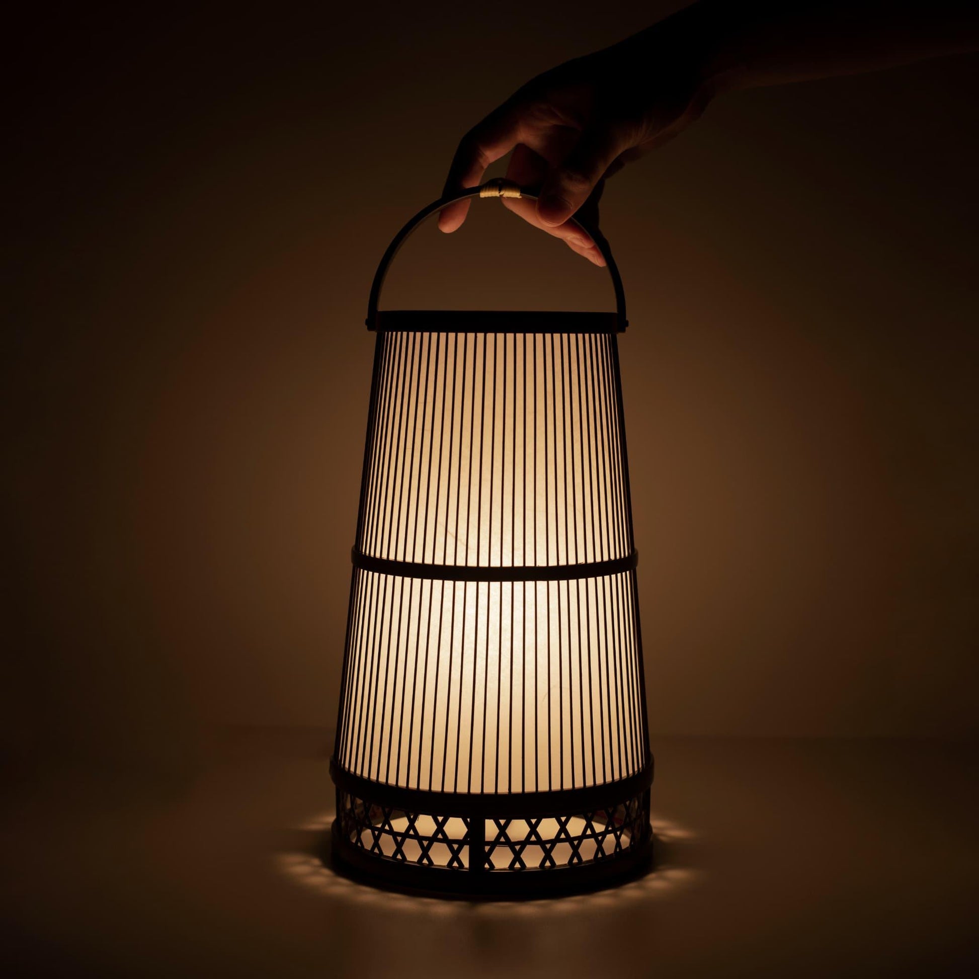 Main tenant une lampe traditionnelle japonaise en bambou, fabriquée à la main à Shizuoka avec des techniques vieilles de 800 ans.