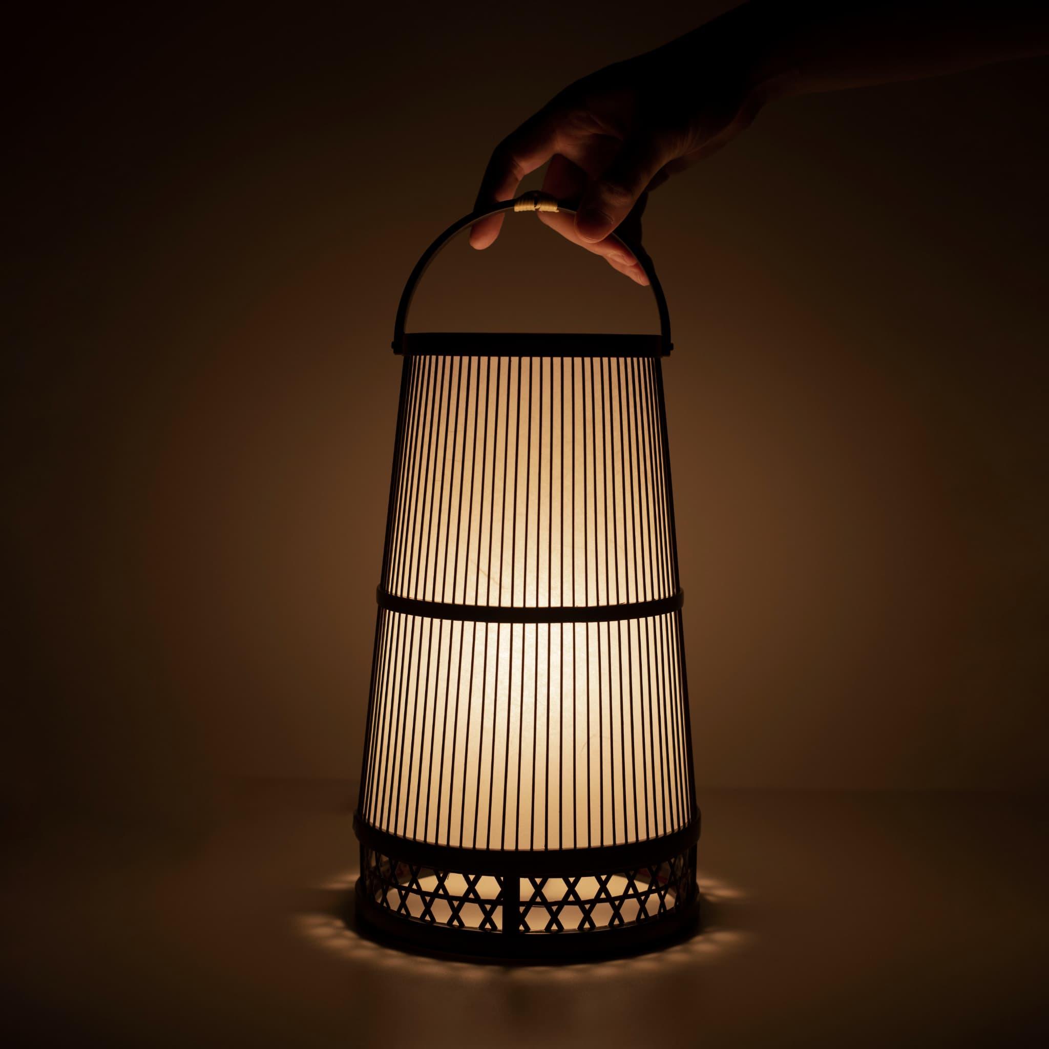 Main tenant une lampe traditionnelle japonaise en bambou, fabriquée à la main à Shizuoka avec des techniques vieilles de 800 ans.