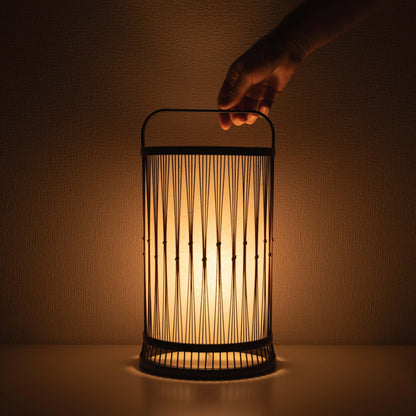 "Hand hält eine traditionelle japanische Bambuslampe, handgefertigt in Shizuoka mit 800 Jahre alten Techniken."
