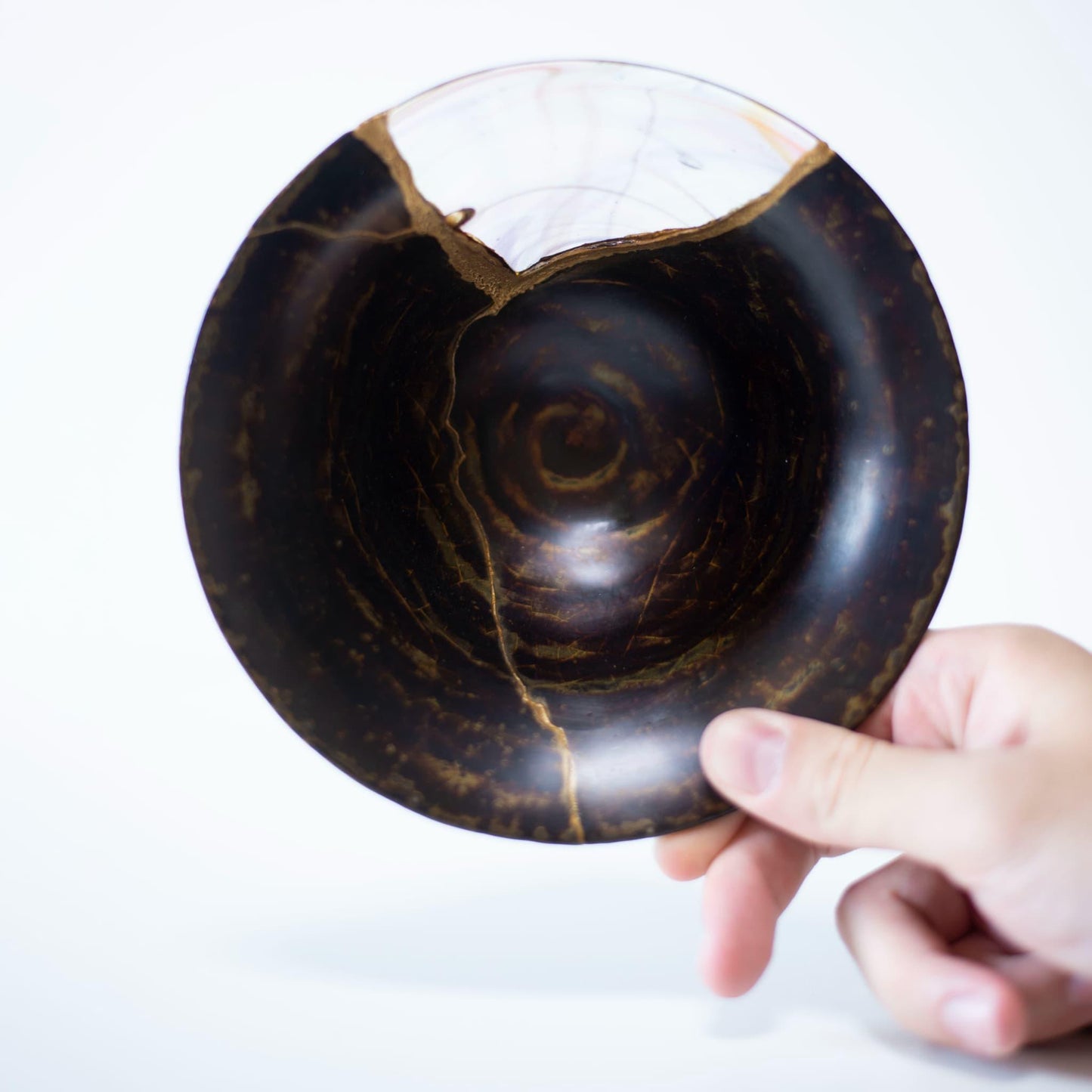 hånd, der holder en Kintsugi-skål, som viser stykkets vægt og balance.