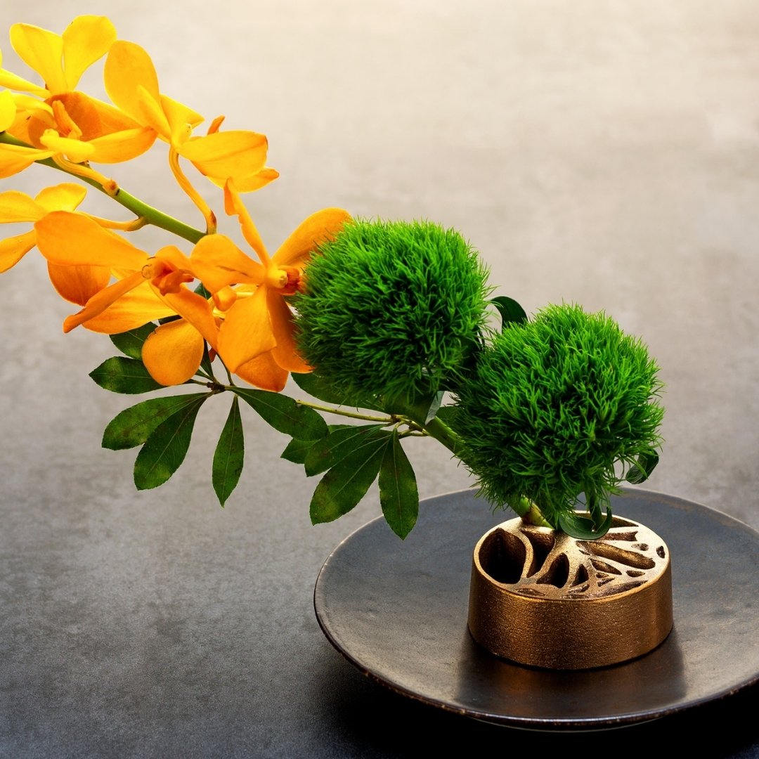 Ikebana blomsterarrangement med japansk pindløs kenzan, ginkgo i japansk vase
