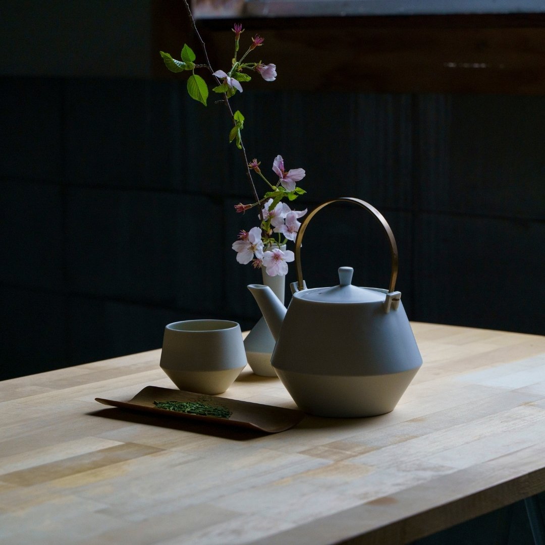 "Japanisches Teekannenset mit Yunomi-Teetassen und Kirschblüten auf Holztisch"