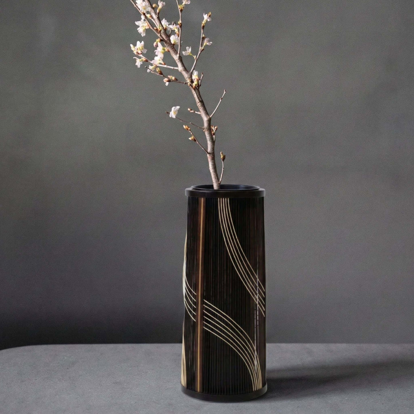 Japansk bambusvase med titlen "Flowing Water" udstillet på et gråt hotelbord.