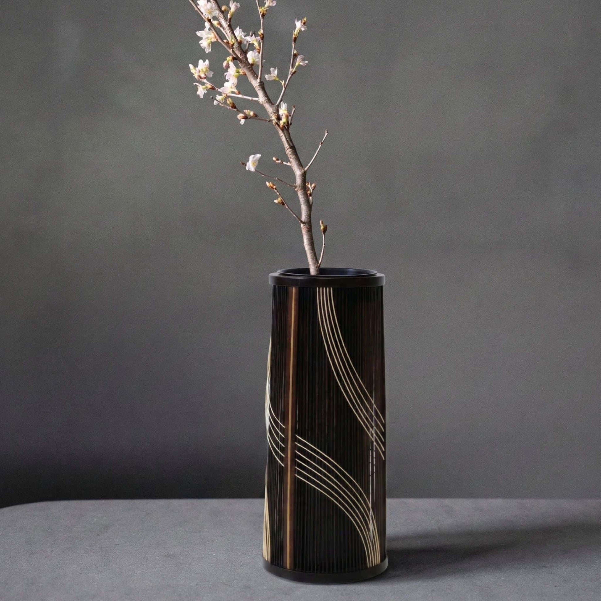 Japansk bambusvase med titlen "Flowing Water" udstillet på et gråt hotelbord.