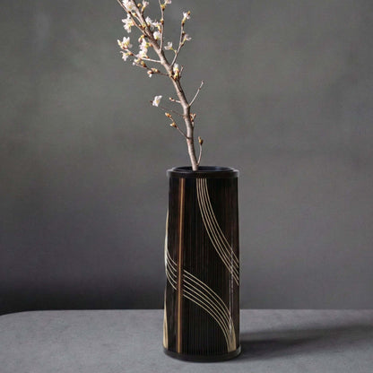 Japansk bambusvase med titlen "Flowing Water" udstillet på et gråt hotelbord.