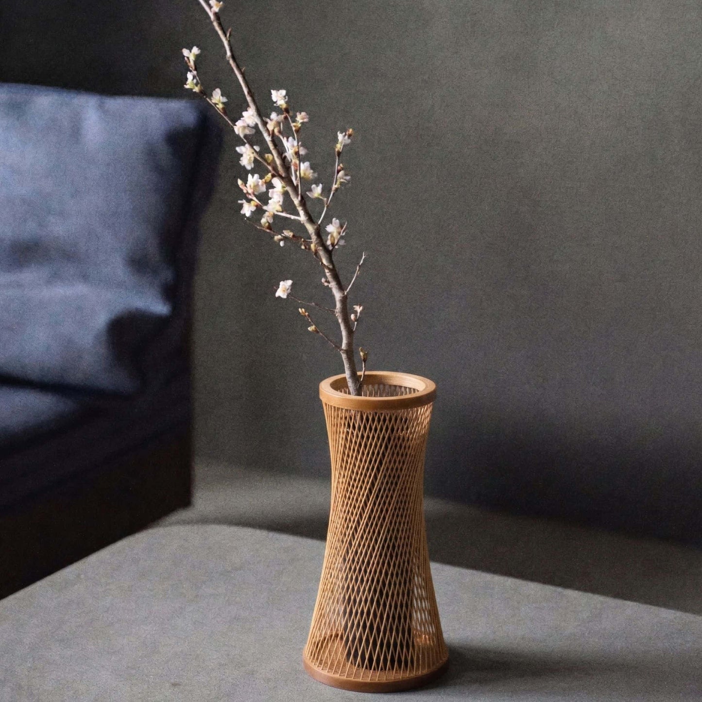 Japansk bambusvase med titlen "Kanon" udstillet på et gråt hotelbord.
