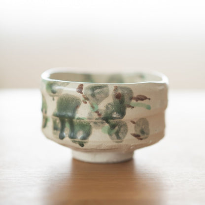 Sidevisning af den japanske matcha-skål "Forest" med mørkegrønne og jordbrune glasurpletter på groft Shino-ler, der fremkalder et mosdækket naturlandskab.