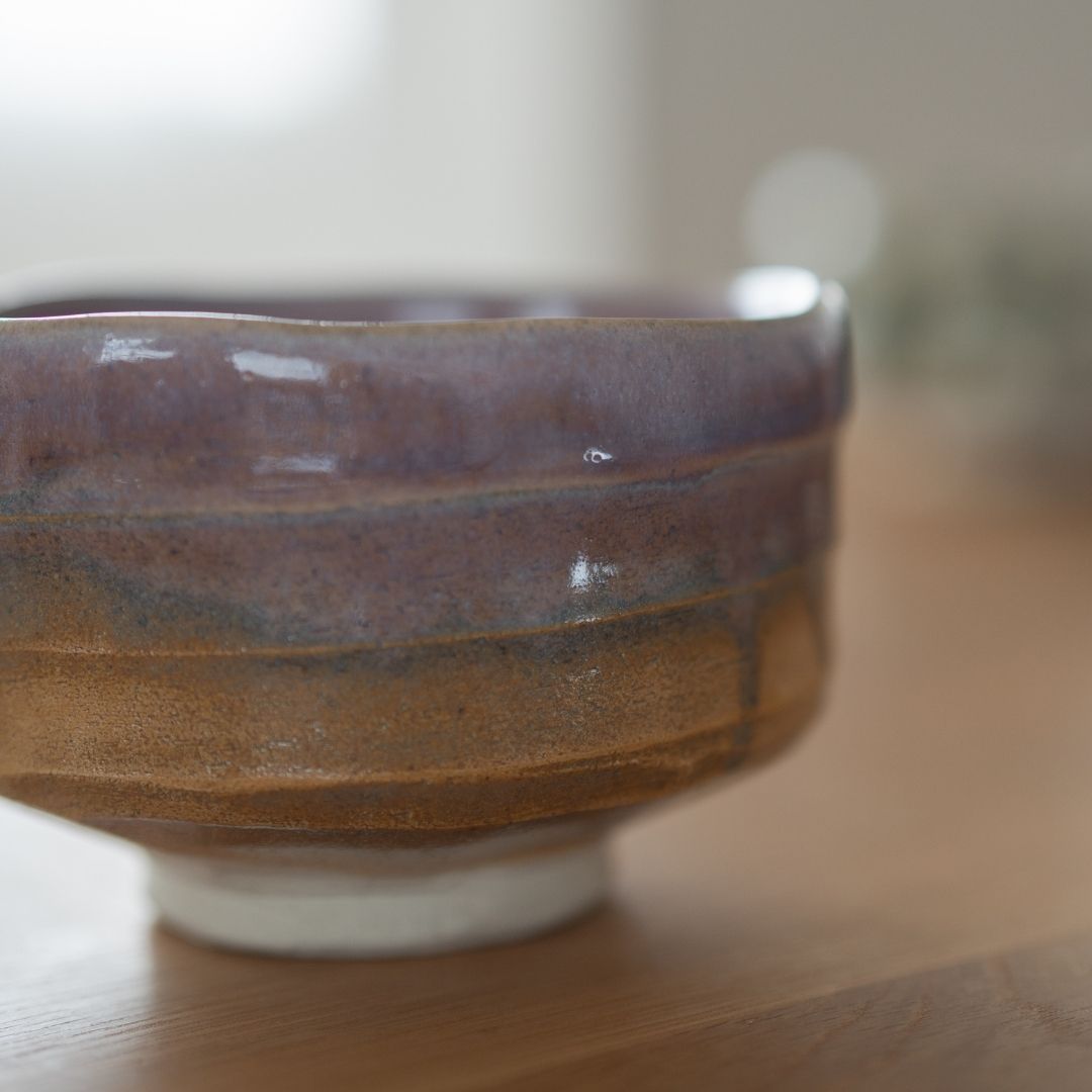 Håndlavet japansk matcha chawan-skål med lys violet og jordfarvet Shino-glasur, der indkapsler wabi sabi-æstetikken.