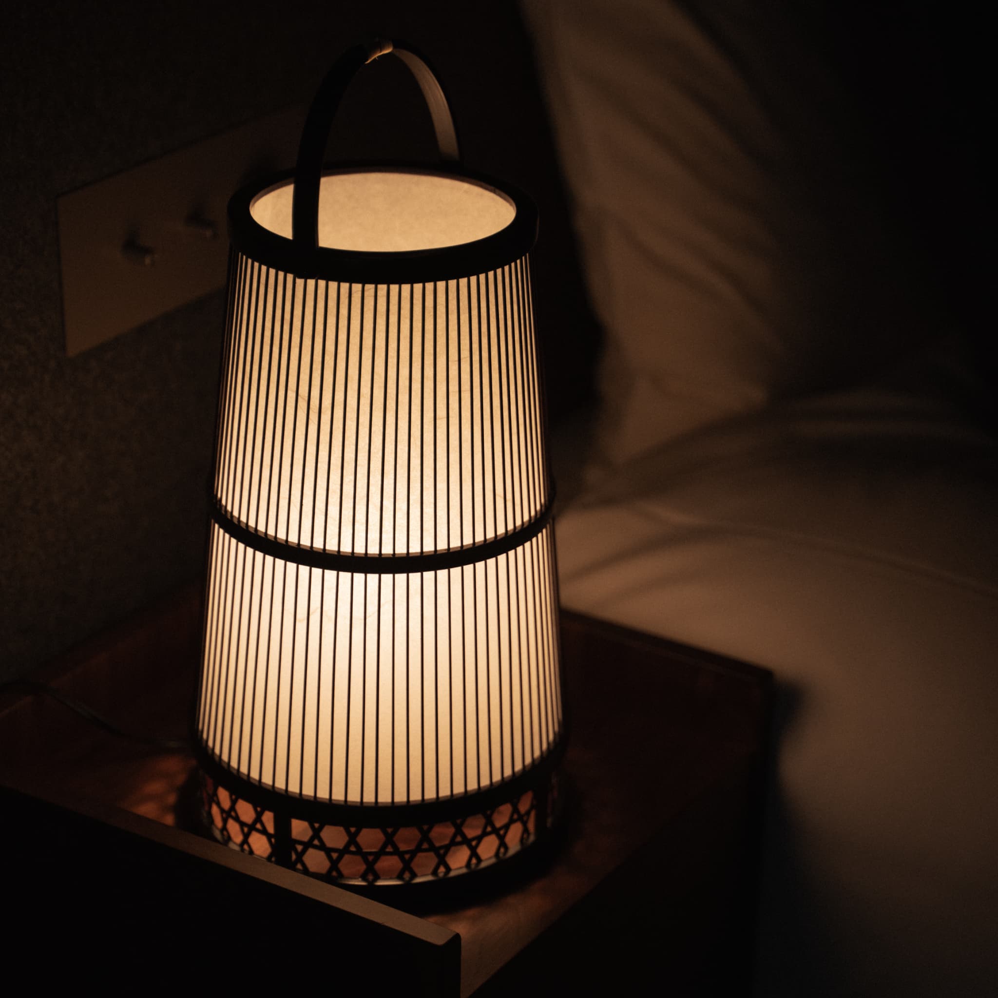 "Lampe de sol japonaise en bambou « Hagoromo » dans une chambre minimaliste de style Japandi." 