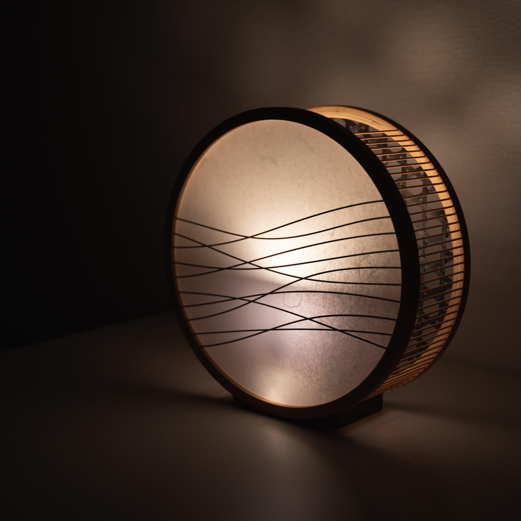 "Lampe japonaise traditionnelle en bambou fabriquée à la main à Shizuoka avec des techniques vieilles de 800 ans. Cadre circulaire en bois avec abat-jour en papier washi orné de délicats accents de bambou." 