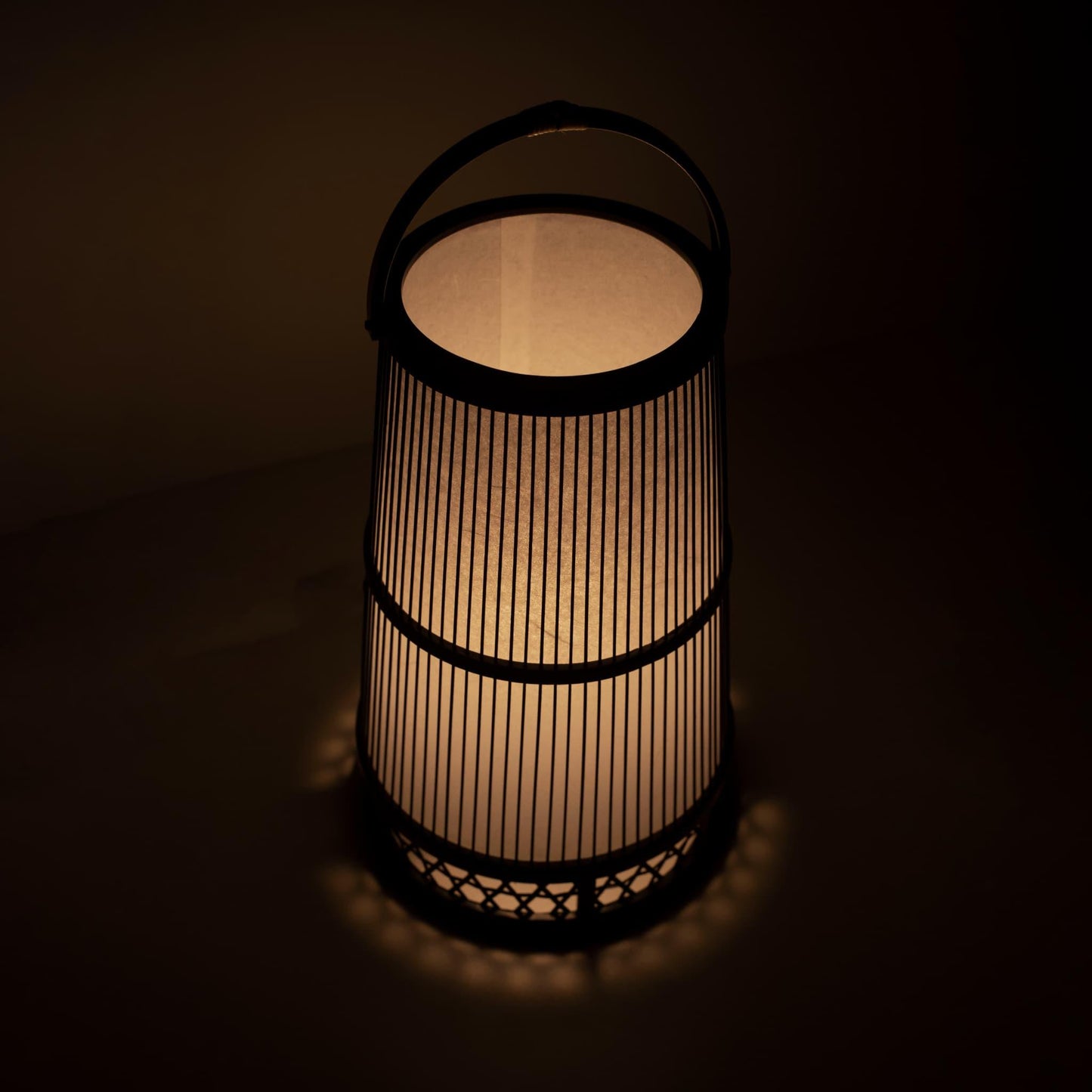 "Lampe japonaise fabriquée avec l'art du bambou de Shizuoka, vieux de 800 ans. De délicates lamelles de bambou créent des motifs complexes, diffusant une lumière chaude à travers le papier japonais."