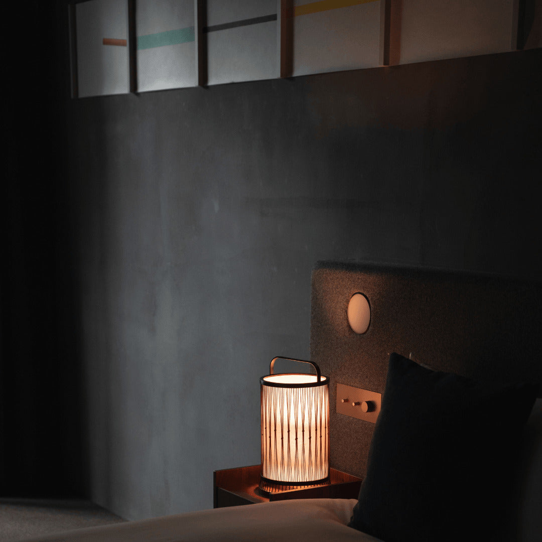 "Eine japanische Bambuslampe auf einem Nachttisch in einem Schlafzimmer im Japandi-Stil."