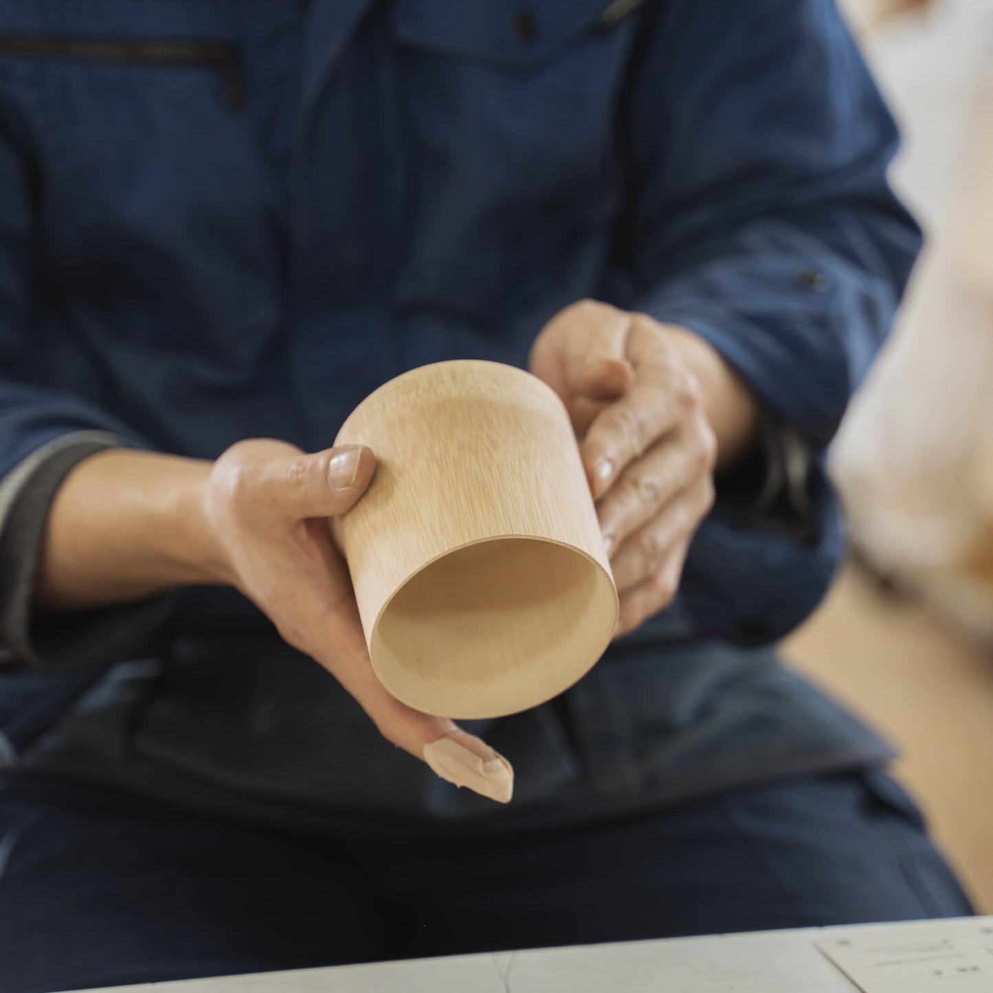 Een hand die een sakebeker van Japans bamboe vasthoudt
