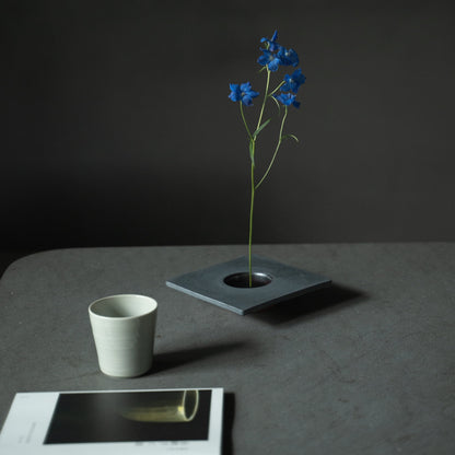 Tæt på en japansk jern ikebana-vase, der viser kenzan (blomsterfrosk) til at arrangere blomster.