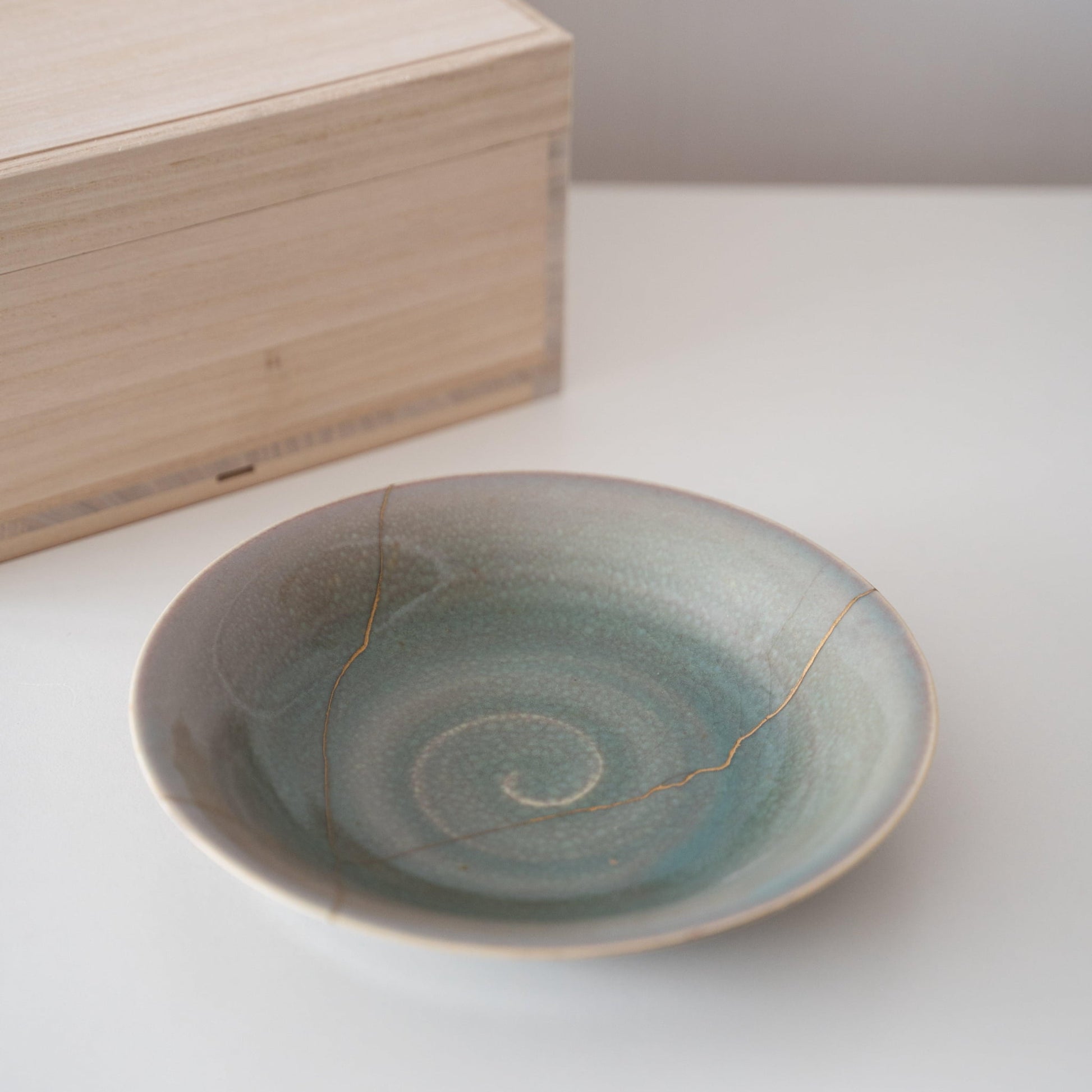 Gavesæt med en sartgrøn skål repareret med Kintsugi, en traditionel japansk teknik, og en paulownia-trææske.
