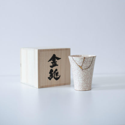 Hvid kop repareret med Kintsugi, en traditionel japansk teknik, præsenteret i en paulownia-trækasse med inskriptionen "Kintsugi".