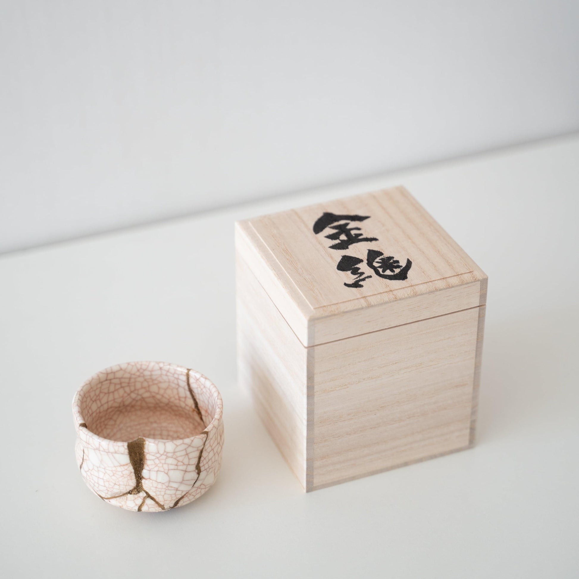Gavesæt med en hvid te-skål repareret med Kintsugi, en traditionel japansk teknik, og en paulownia-trækasse.