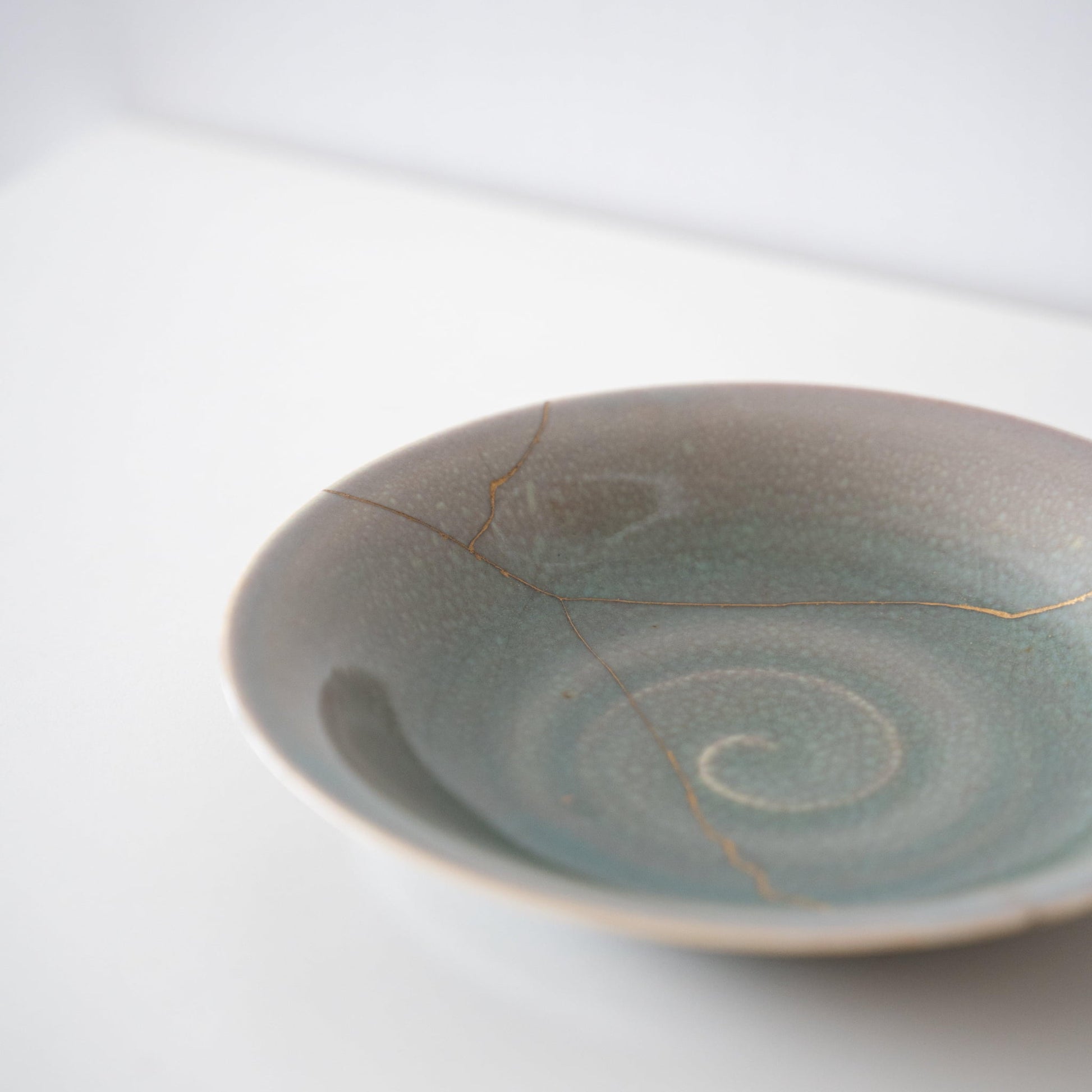 Lys grøn skål repareret med Kintsugi, en traditionel japansk teknik.