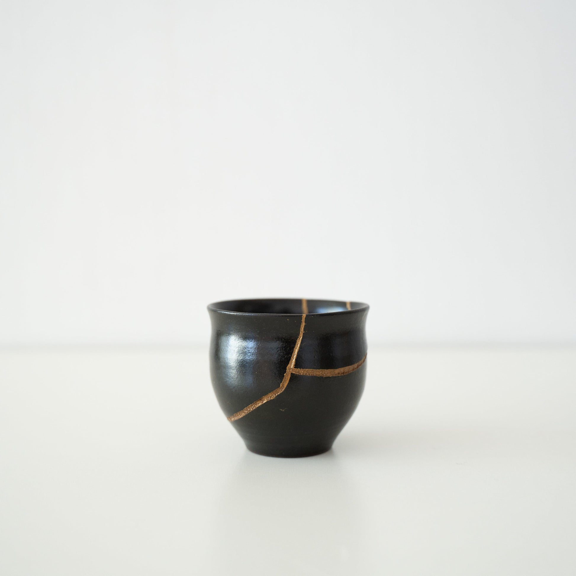 Japansk sakekop ved navn "Shikkoku Rai" (Kulsort Torden), repareret med guldlak ved hjælp af den traditionelle Kintsugi-teknik.