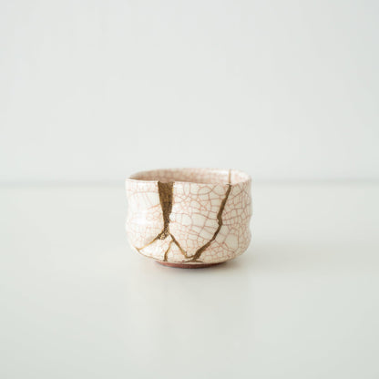 Hvid te-skål repareret med Kintsugi, en traditionel japansk teknik, der viser det gyldne samlingspunkt.