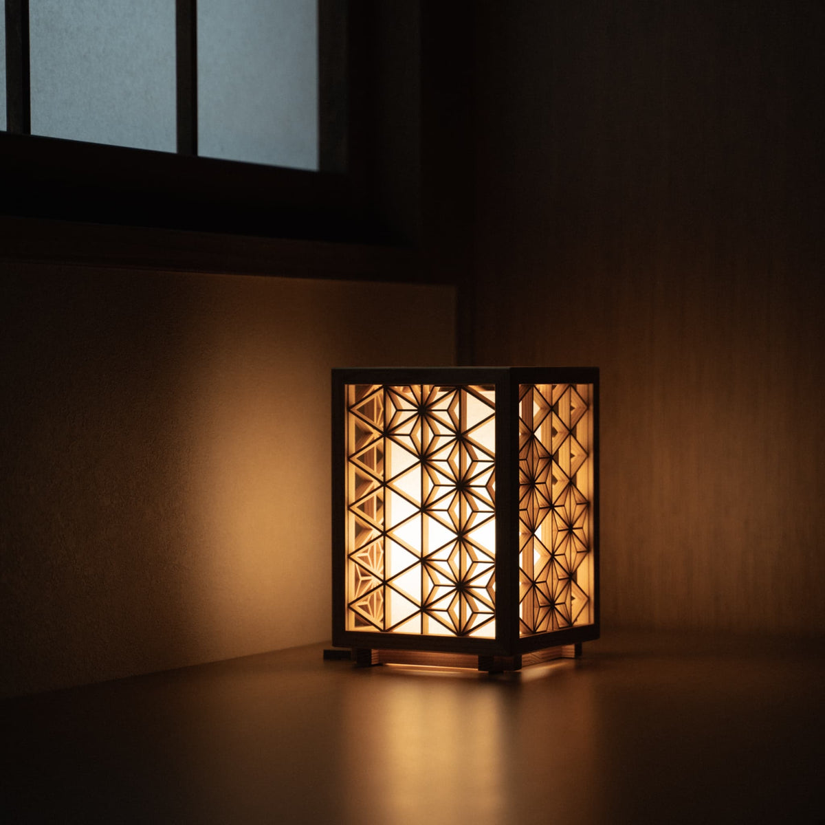 Japanse Kumiko lamp "Asanoha" klein die een warme gloed afgeeft in een schemerige woonkamer in Japanse stijl