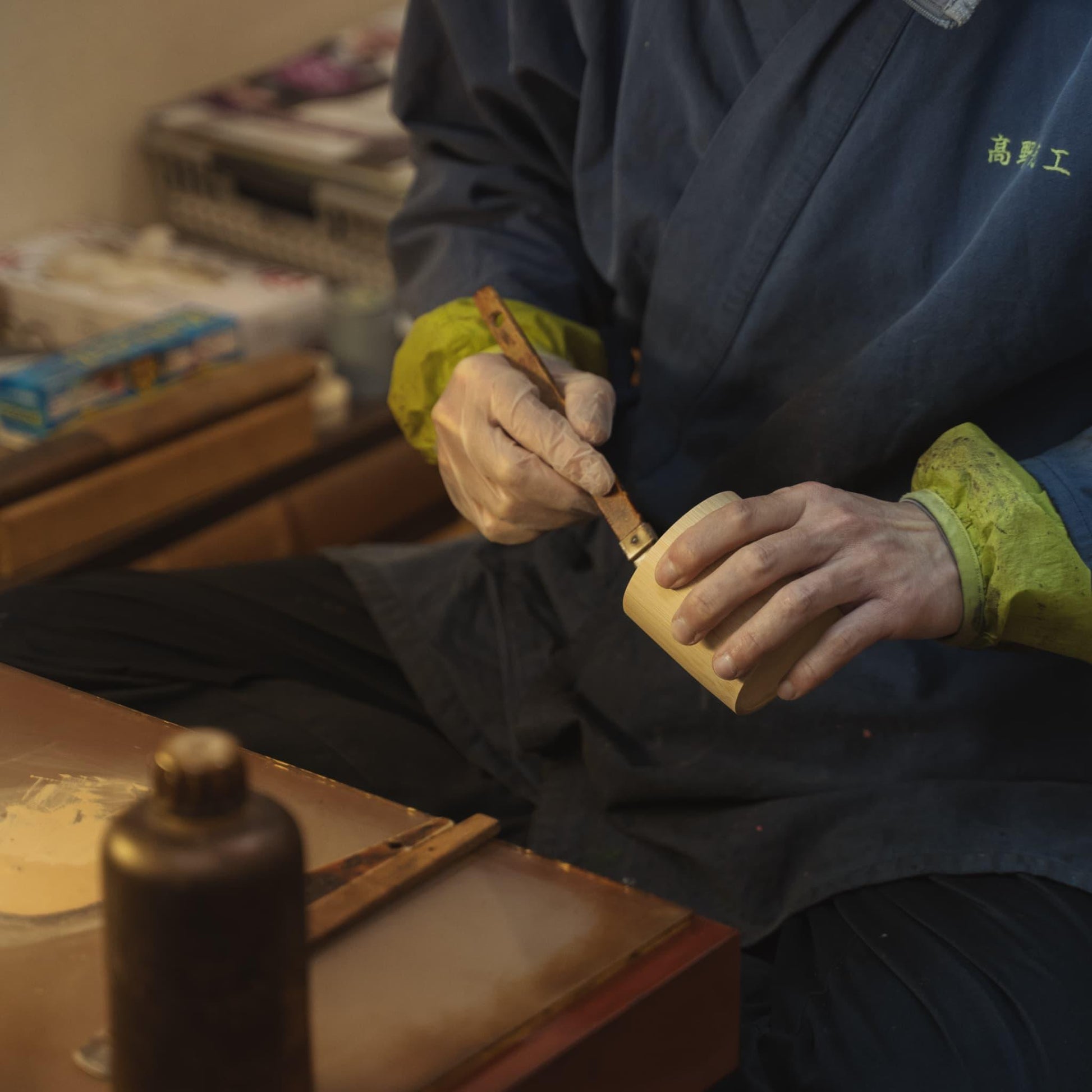Japanse ambachtsman brengt lak aan op een bamboebeker, met traditioneel vakmanschap.
