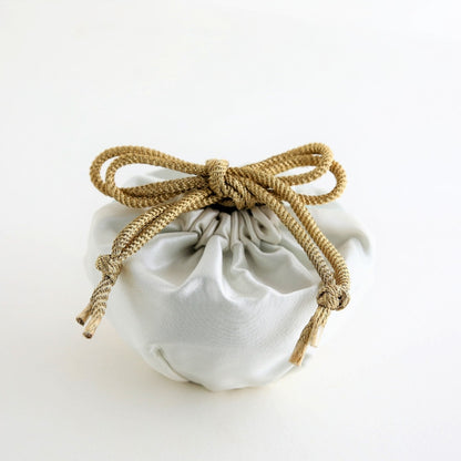 japansk matcha-skål "Waraku" indpakket i en elegant silkepose med en gylden snor, der repræsenterer den raffinerede skønhed og tradition fra Mino Ware keramik.