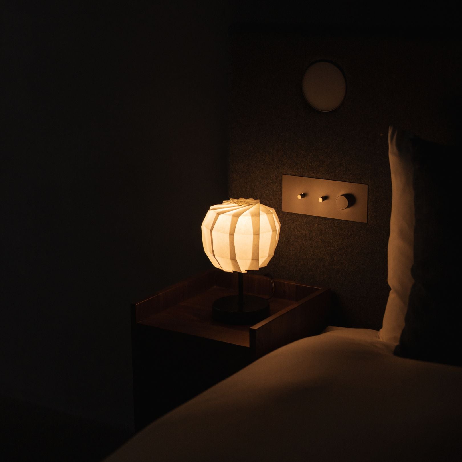 Japanse papieren tafellamp "Bloem van Licht maru met standaard" op een houten nachtkastje